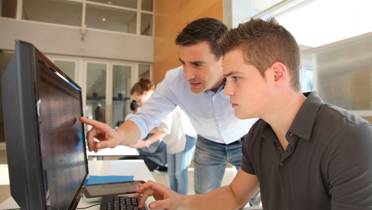 A man showing a younger man something on a computer's screen