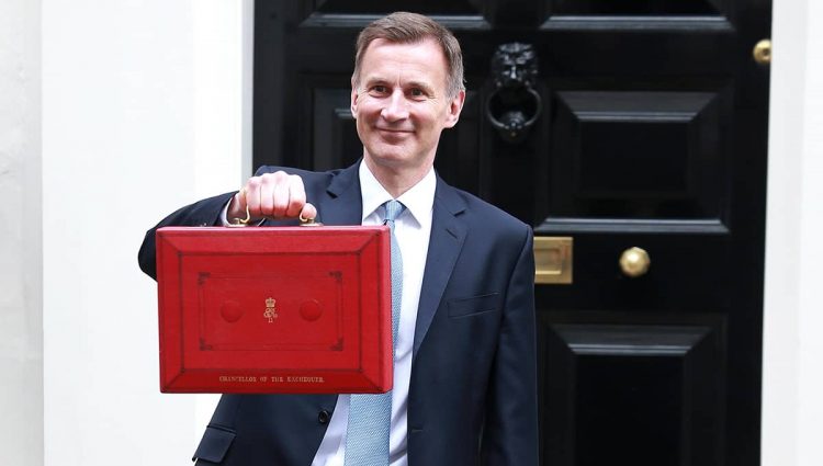 Jeremy Hunt holding a red Budget Box in front of the door no No.11 Downing Street