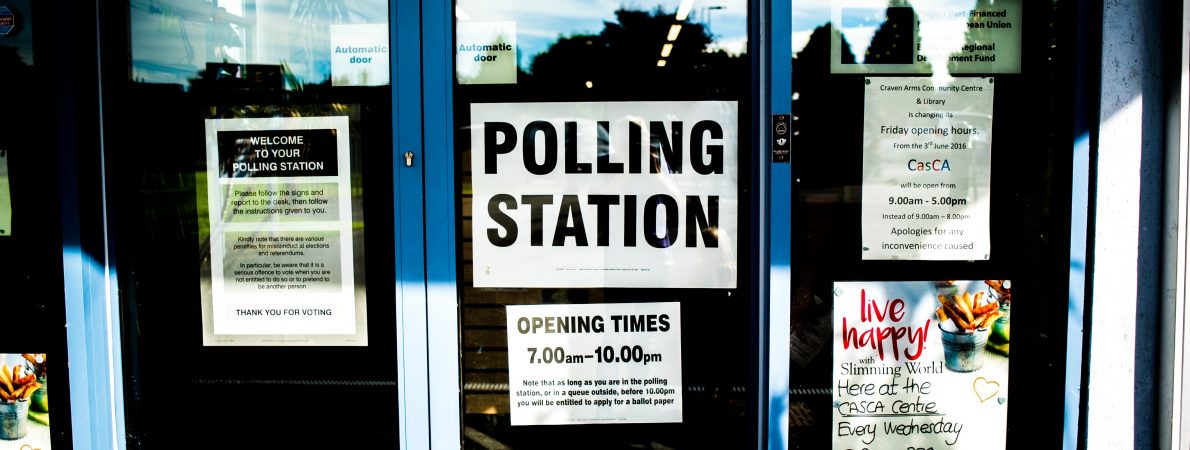 A sign reading 'Polling station' on the front of a clear glass door.
