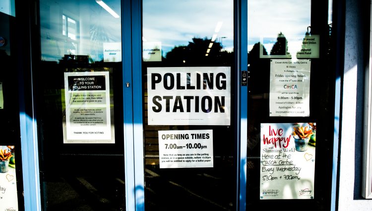 A sign reading 'Polling station' on the front of a clear glass door.