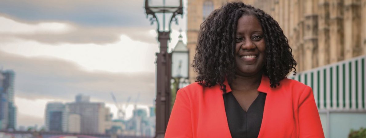 Marsha De Cordova stands on the terrace of Parliament, with the House of Commons on the right and the river Thames on the left.