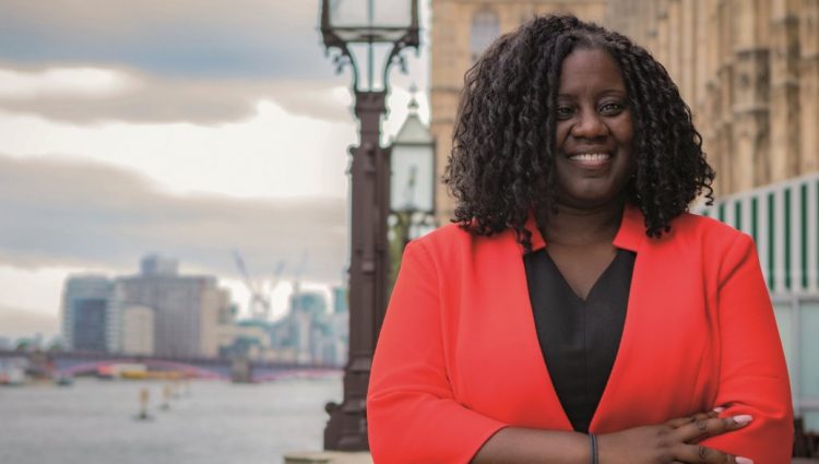 Marsha De Cordova stands on the terrace of Parliament, with the House of Commons on the right and the river Thames on the left.