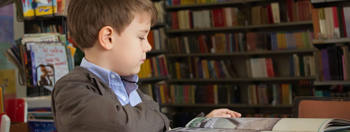 A young child reading a book in a library
