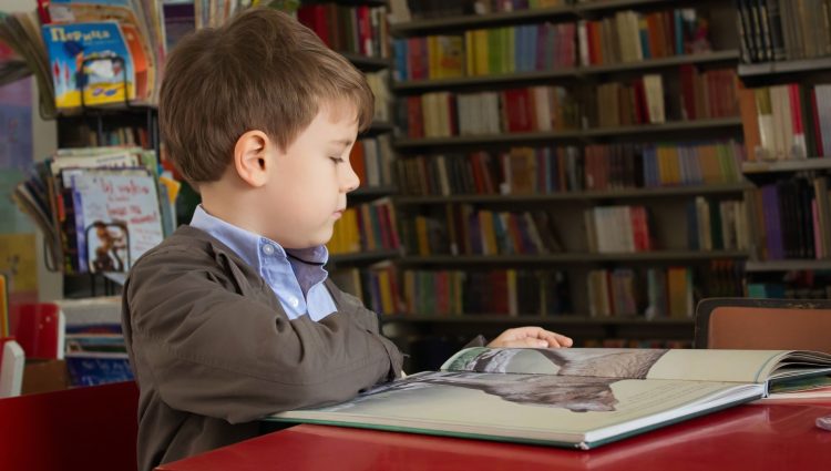 A young child reading a book in a library