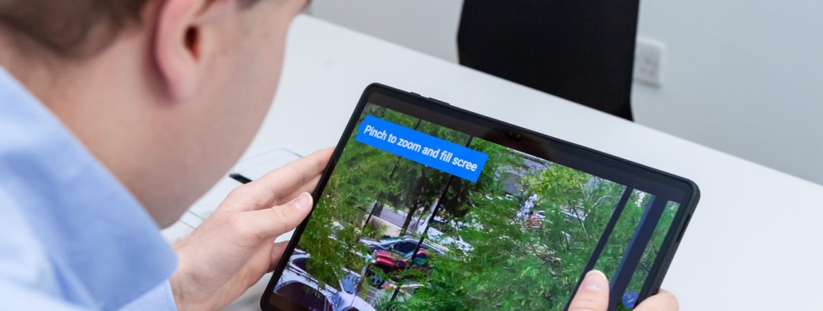 A close-up of a visually impaired man using a tablet and its zoom in feature to see something