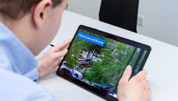 A close-up of a visually impaired man using a tablet and its zoom in feature to see something