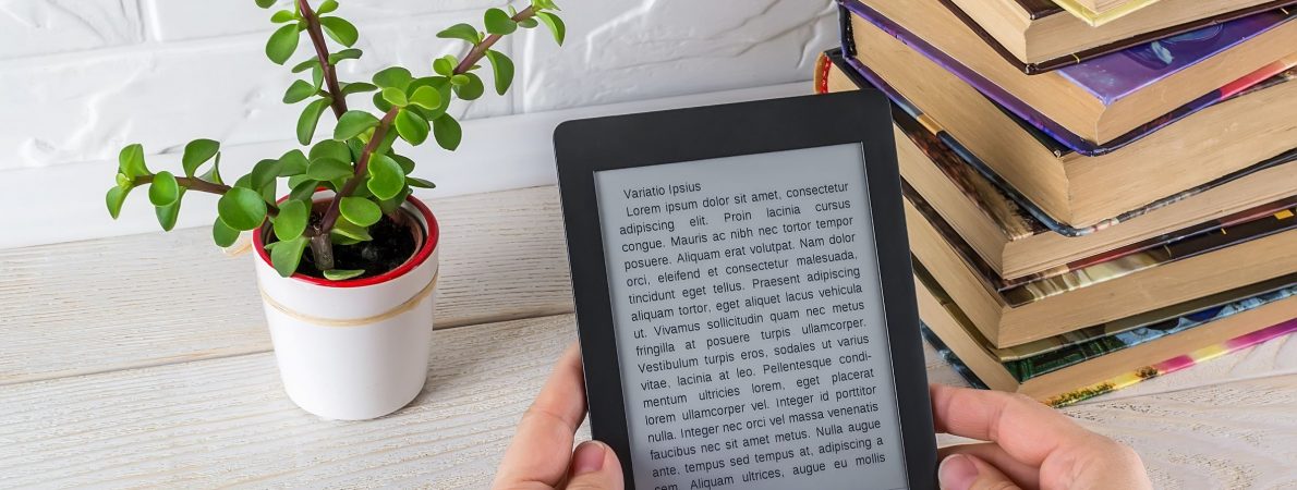 Text shown in a tablet's screen, a desk with a plant and some books on it