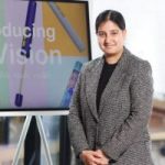 Picture of Ramneek smiling in front of a screen that says 'Introducing My Vision'