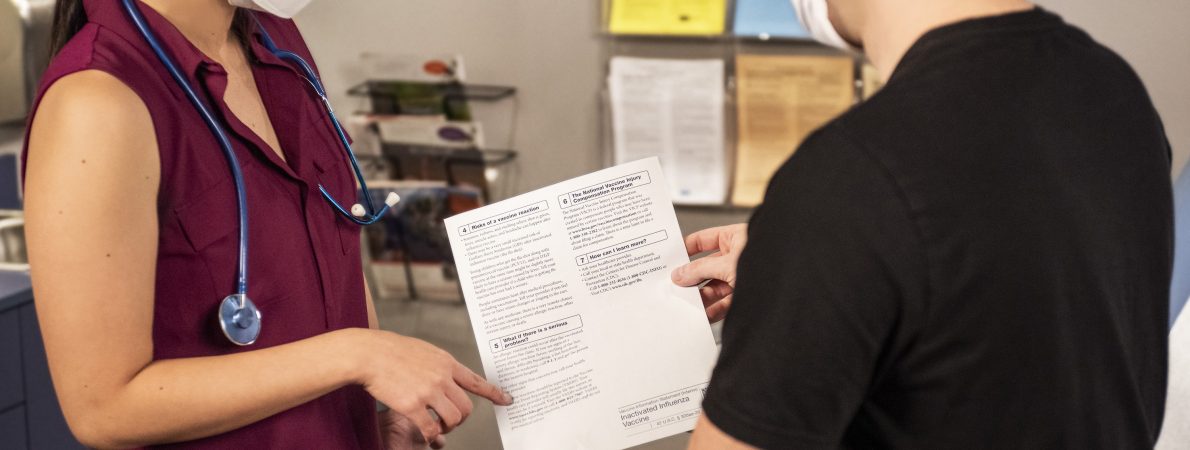 A doctor and patient converse over a medical document