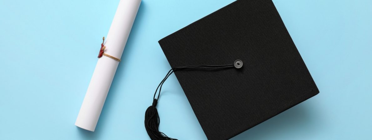 A graduation hat and a diploma on a blue background