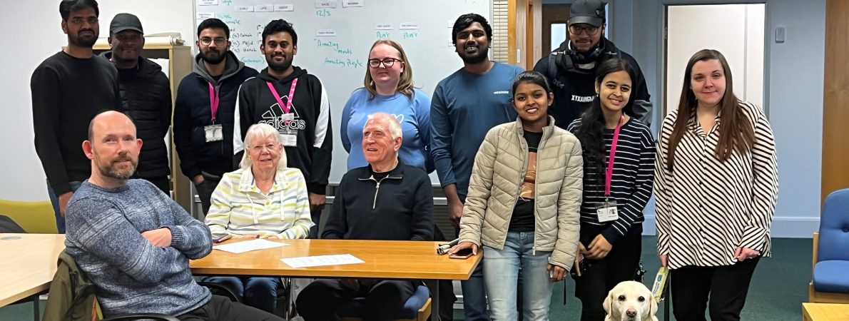 Image shows Bedfordshire Sight Loss Council members and Ethos Farm employees posing for a photograph. There is a mix of people of different ages and ethnicities, some are standing and some are seated. Samantha Leftwich, Engagement Manager for the East, is stood with her guide dog on her right.