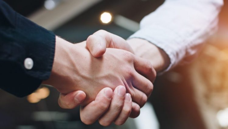 Photograph shows two men shaking hands.