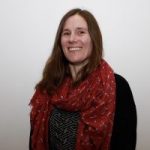 Head and shoulders picture of Louise, wearing a red scarf and smiling at the camera.