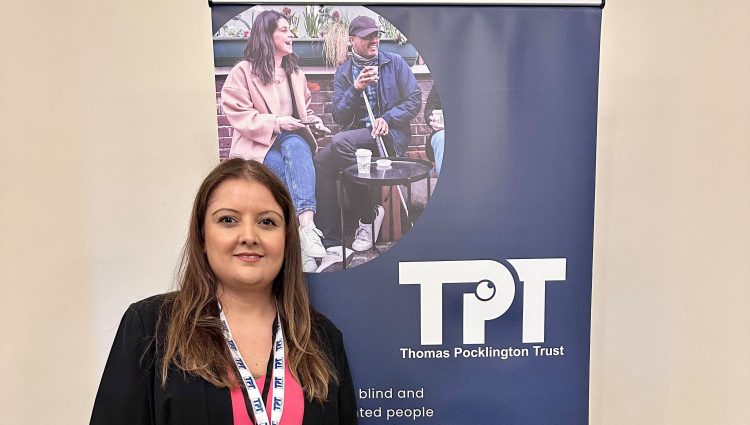 Bhavini Makwana, Campaigns Manager for TPT stood in front of a TPT banner.