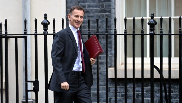Jeremy Hunt holding the ministerial box and walking on the street, looking at the camera.