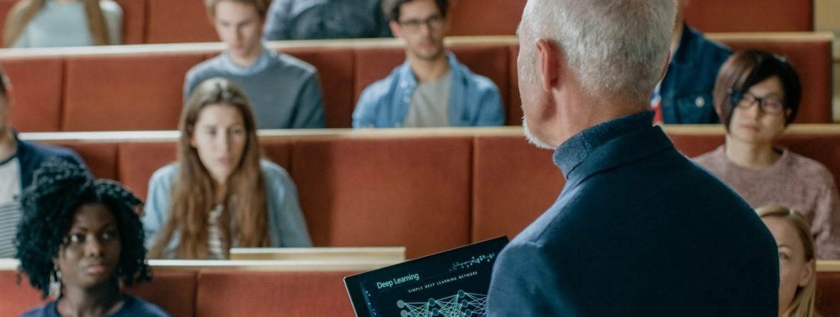 Professor of Computer Science Reads Lecture from a laptop to a Classroom Full of Multi Ethnic Students.