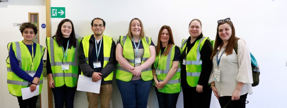 A group of six volunteers and one of our Sight Loss Councils Engagement Manager with her guide dog, all smiling at the camera.