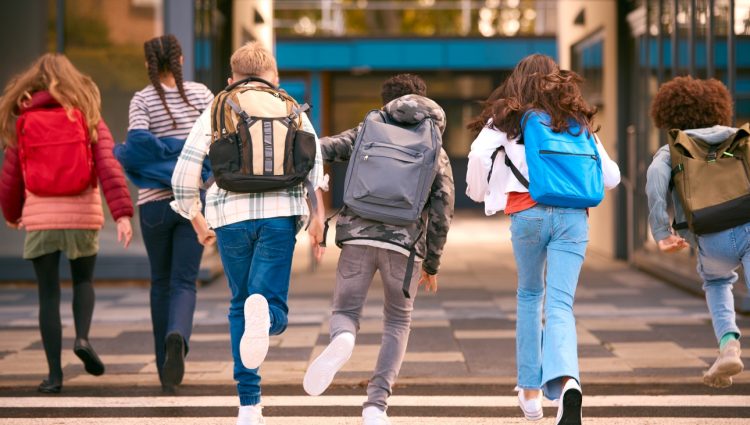 Group Of Secondary Or High School Pupils Running Away From Camera Outside School Building