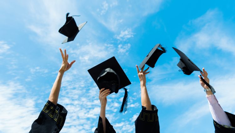 A picture of some graduation hats being thrown into the air, agaisnt a bright blue sky.