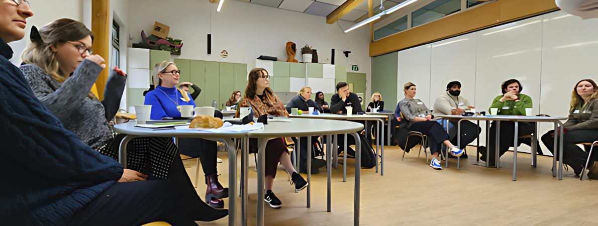 A low angle shot of a bright classroom or learning space for adults at the Royal Parks. People are facing forwards looking at a speaker not shown in the photo.