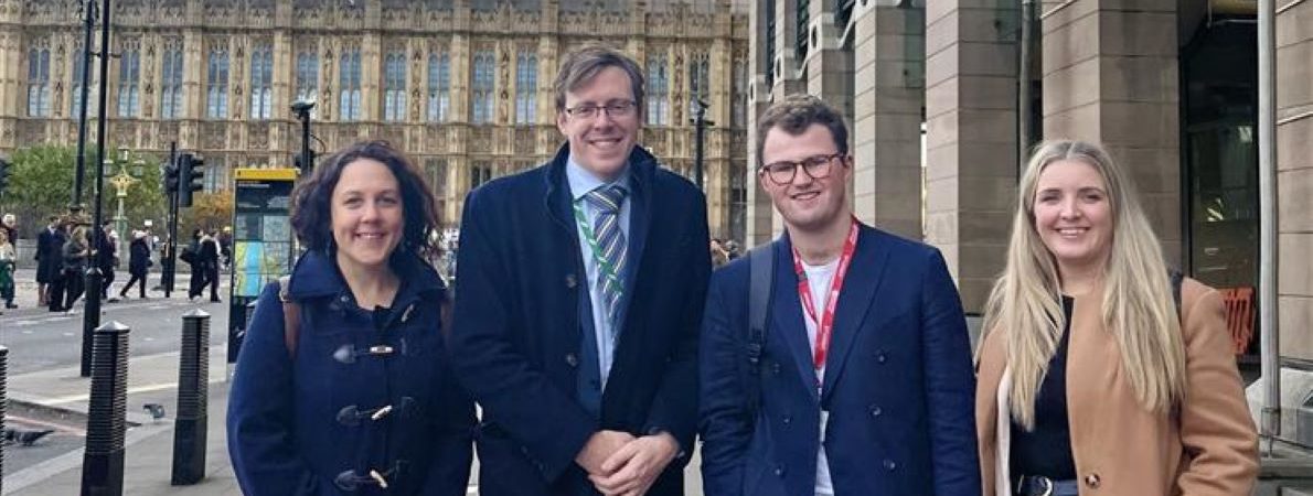 A picture of Tom standing in front of a Parliament building, having a great time with Kate and James Nash.