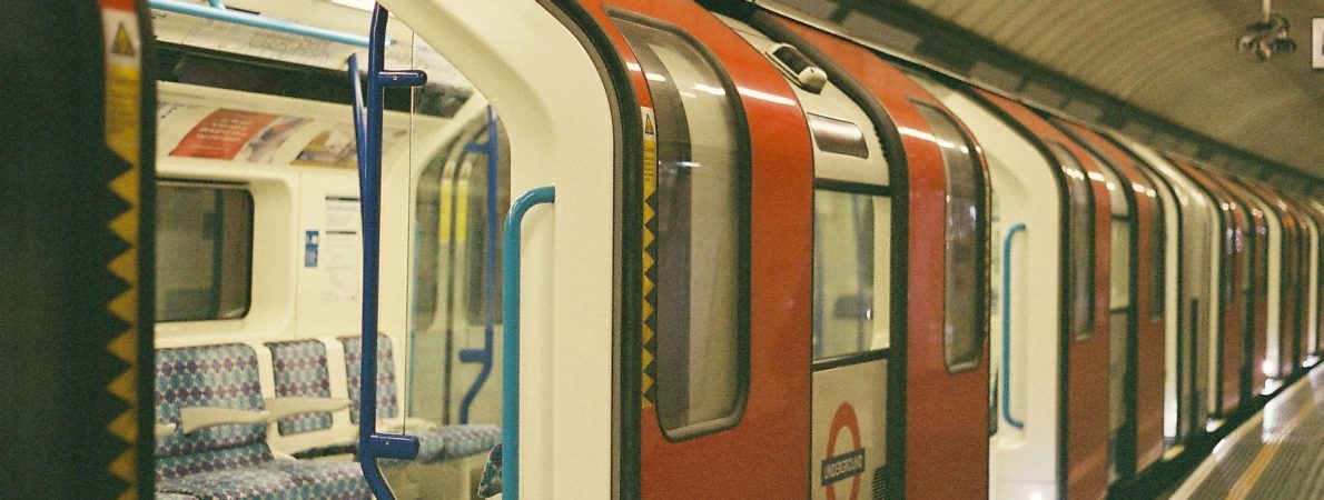 An empty London Underground train carriage sits waiting at a platform, with the doors open.