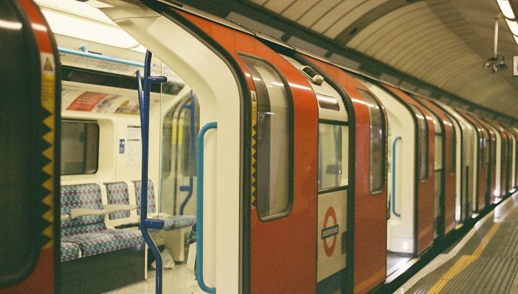 An empty London Underground train carriage sits waiting at a platform, with the doors open.