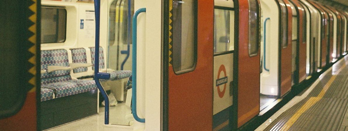 An empty London Underground train carriage sits waiting at a platform, with the doors open.