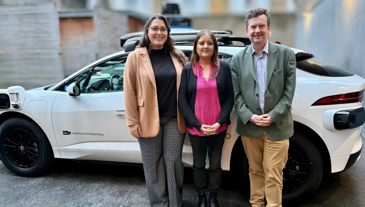 Amanda from Waymo, Bhavini, our Policy and Campaigns Manager and Charles, our CEO stand side by side in front of a white, electric Waymo car.