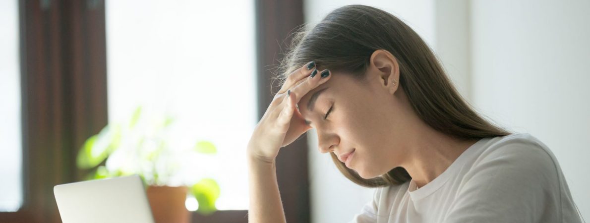 A picture of a young woman despairing in front of a laptop