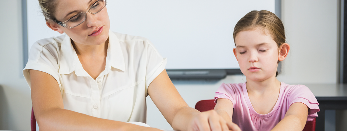 Woman reading with braille with a young girl