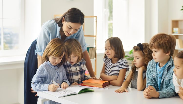 Young school teacher helping her students who are writing in notebooks. | links to article: Top Tips for Primary School