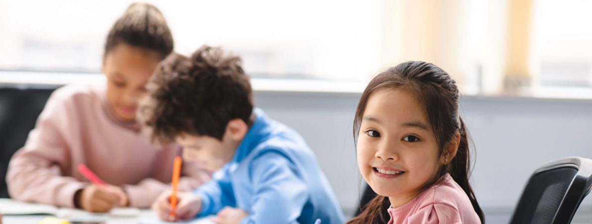 A young girl smiling at the camera in a classroom