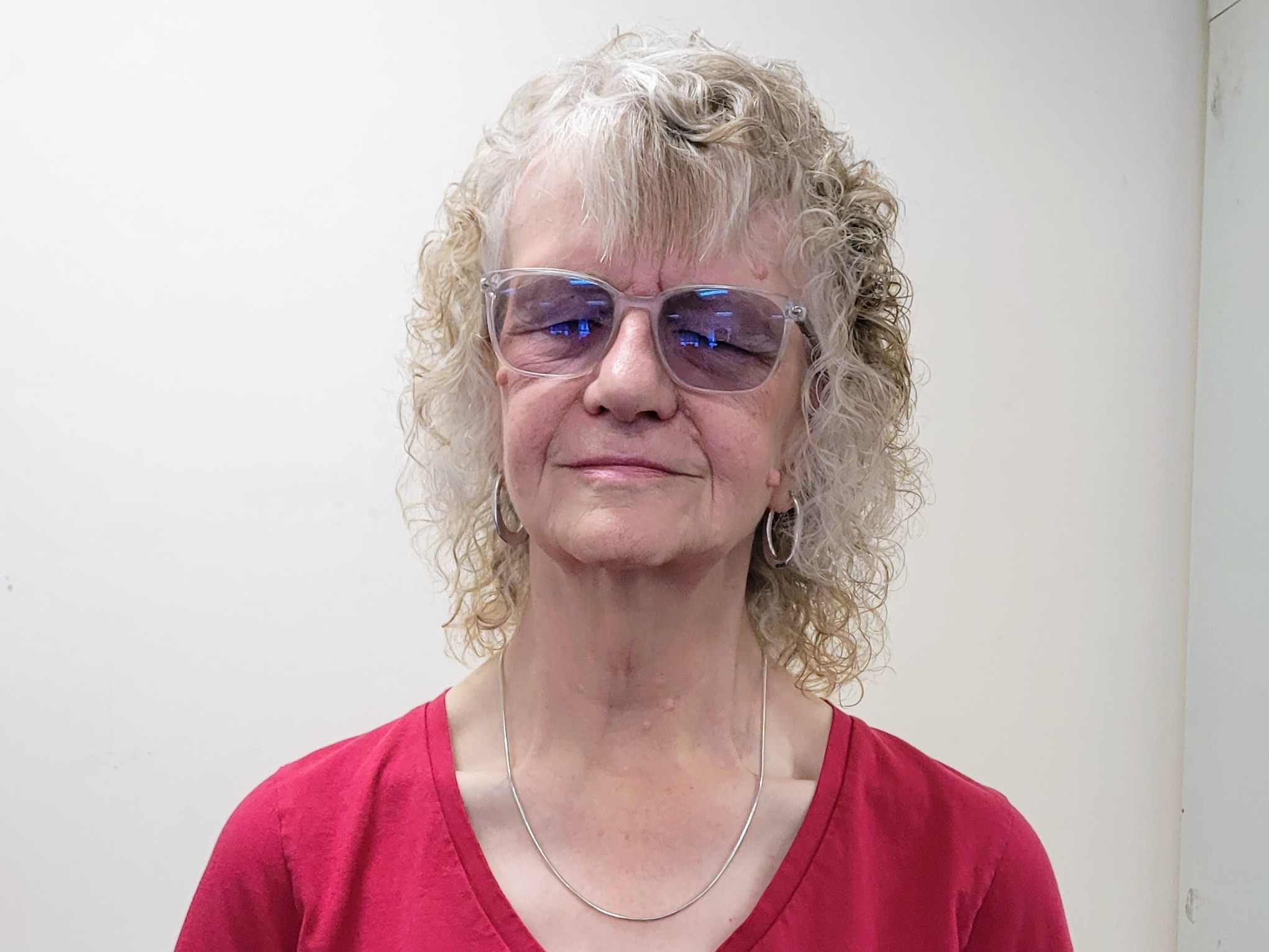 Headshot of Heather Armstrong, West of England SLC member. She is wearing a red jumper and glasses, standing against a white wall.