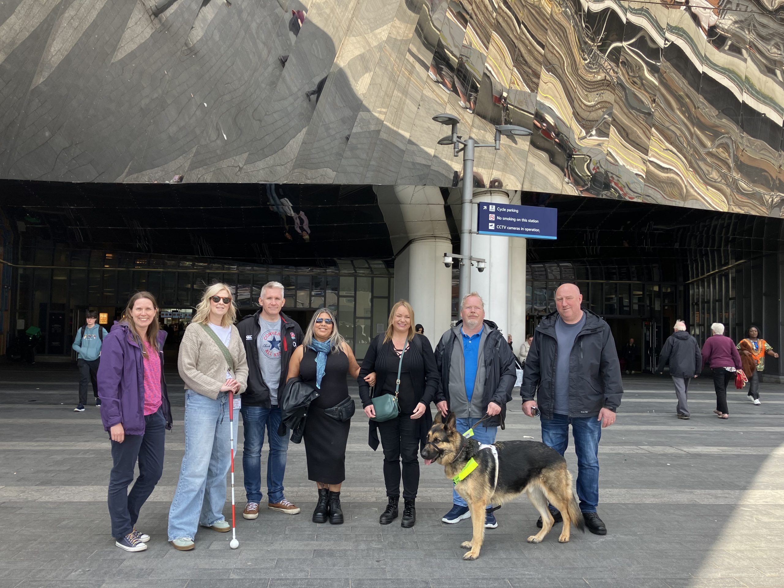 Members of Birmingham and Black Country SLC stood with staff from West Midlands Police in plain clothes, as well as a policeman in a yellow high-visibility jacket. They are all facing the camera, smiling, in Birmingham City Centre.
