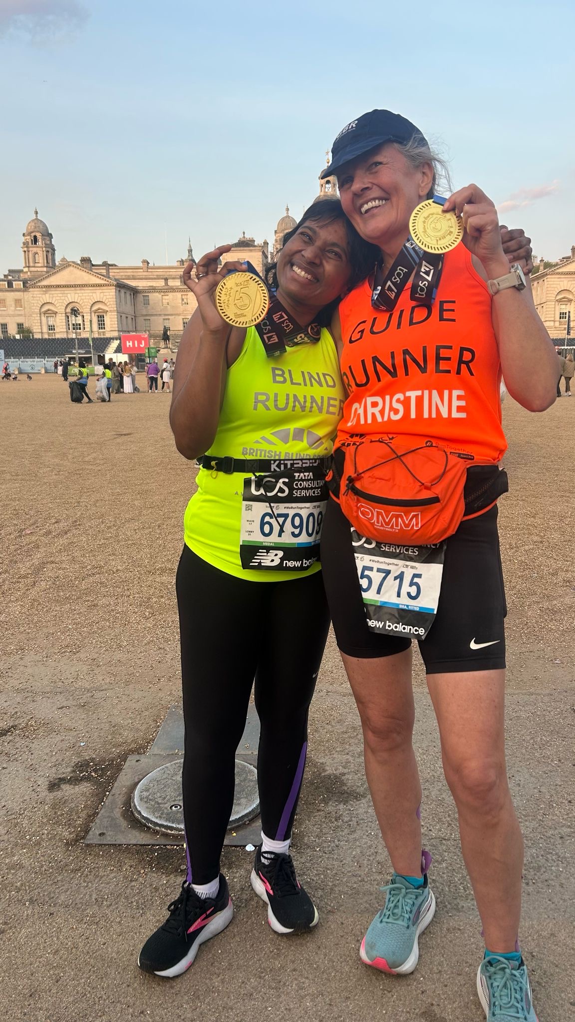Deepika with guide runner smiling happily at the end of the race holding their marathon medals.