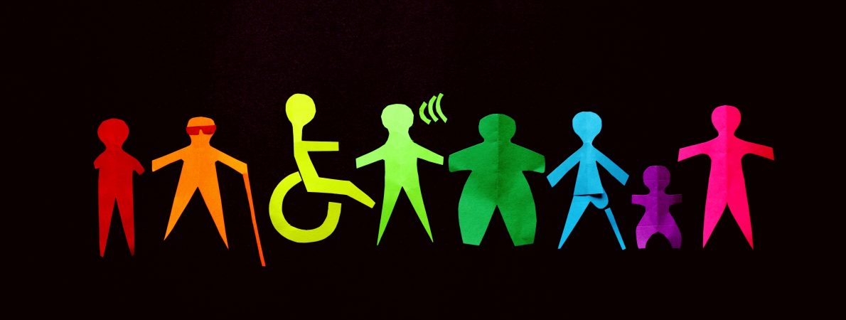 Colourful paper cut-out figures representing diverse people and abilities on a black background. Each one is a different shade of the rainbow, and includes an orange figure with a long cane, a yellow-green figure in a wheelchair, and a green hard of hearing figure.