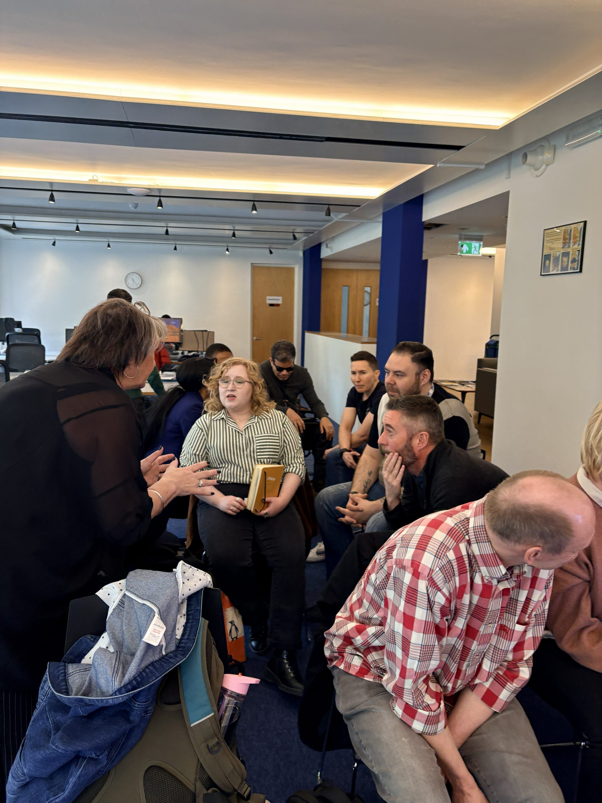 the session trainer engaged with learners sat in a circle of all different backgrounds